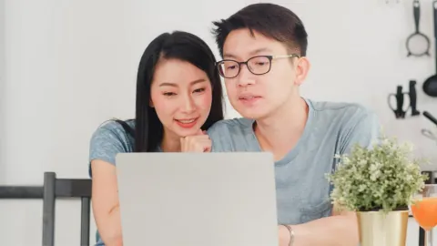 A couple looking at homes together on a laptop in their kitchen
